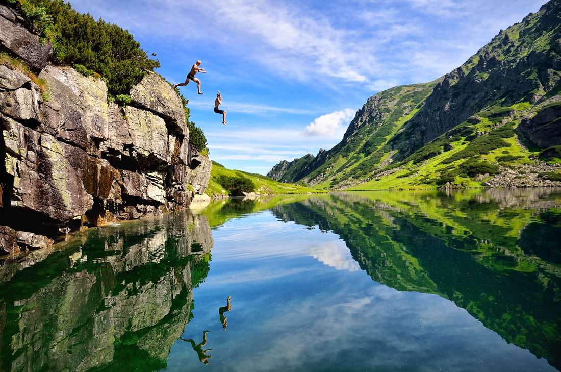 Man and woman jumping into river off a cliff